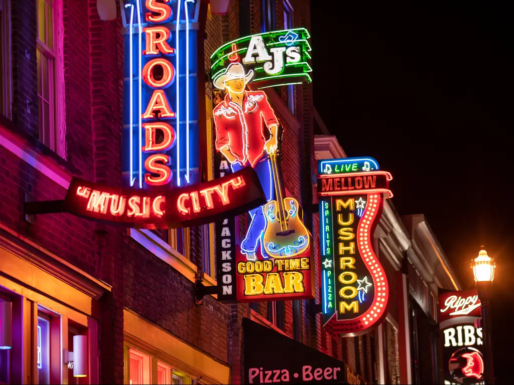 Nashville, Tennessee, USA with colorful neon store signs hang along the bars restaurants and record stores along Broadway Street in downtown Nashville.