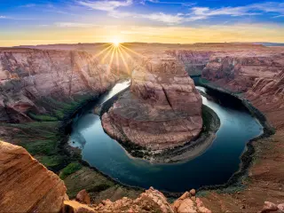 Grand Canyon National Park, USA at sunset showing the Horseshoe bend with the Colorado River around the rock formation and canyons in the distance.