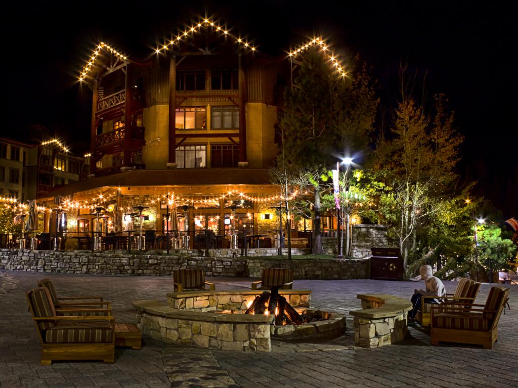 A man is sitting alone at a street fireplace outside the Village Lodge in Mammoth Lakes, California.