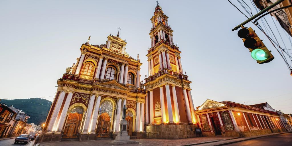 The red and gold exterior of the Basilica and Convent of San Francisco in Salta, Argentina, with a car and traffic light also in shot