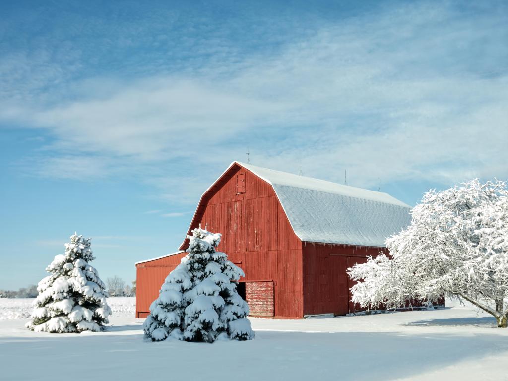 A rustic red barn in Ohio covered in fresh snow with a bright blue sky background
