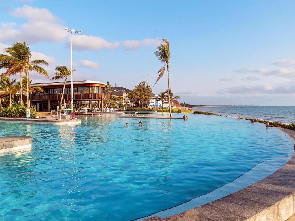 Swimmers at early morning at the lagoon with infinity edge pool on the beach