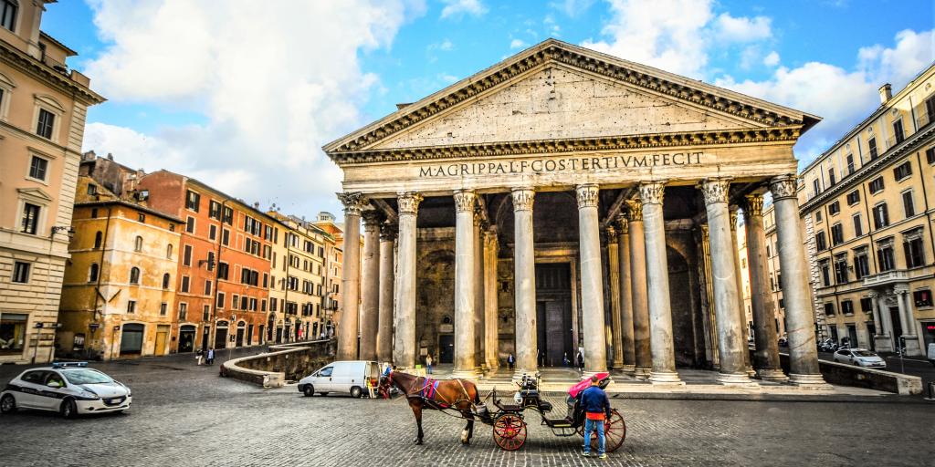 A view of the column fronted Pantheon, Rome, with blue skies and a horse and cart in the foreground