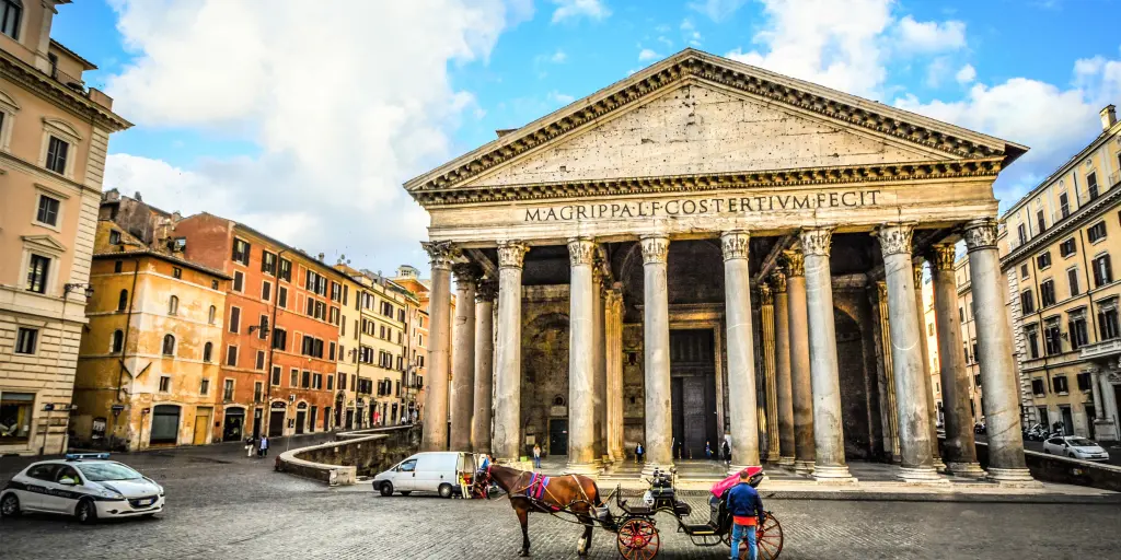 A view of the column fronted Pantheon, Rome, with blue skies and a horse and cart in the foreground