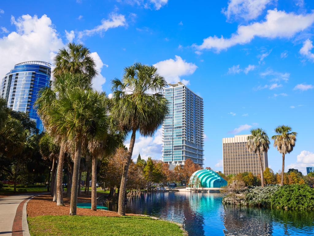 Orlando, Florida, USA with the city skyline in the background and Lake Eola in the foreground, with grass and palm trees and taken on a sunny day.