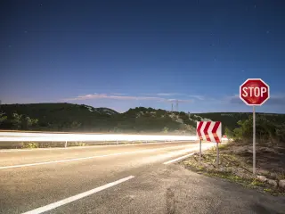 A stop sign on the side of a road at night 