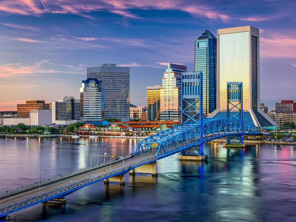Jacksonville, Florida, USA with the downtown city skyline in the distance, the bridge crossing the river in the foreground and taken at sunset.