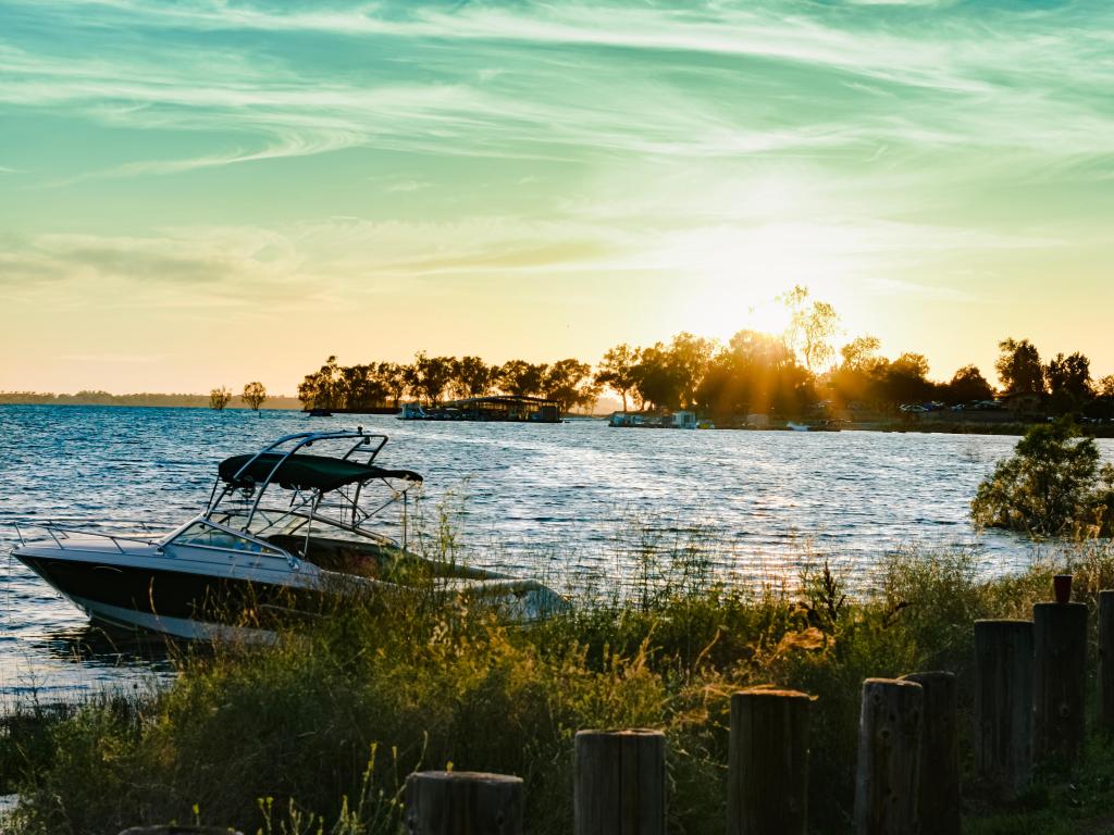 A boat sets off from the shore at sunset at Camanche Reservoir, with calm blues waters