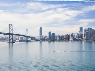 San Francisco, California, USA with a boat in the water in the foreground and the city skyline is the distance, the bridge to one side on a sunny day.