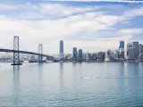 San Francisco, California, USA with a boat in the water in the foreground and the city skyline is the distance, the bridge to one side on a sunny day.