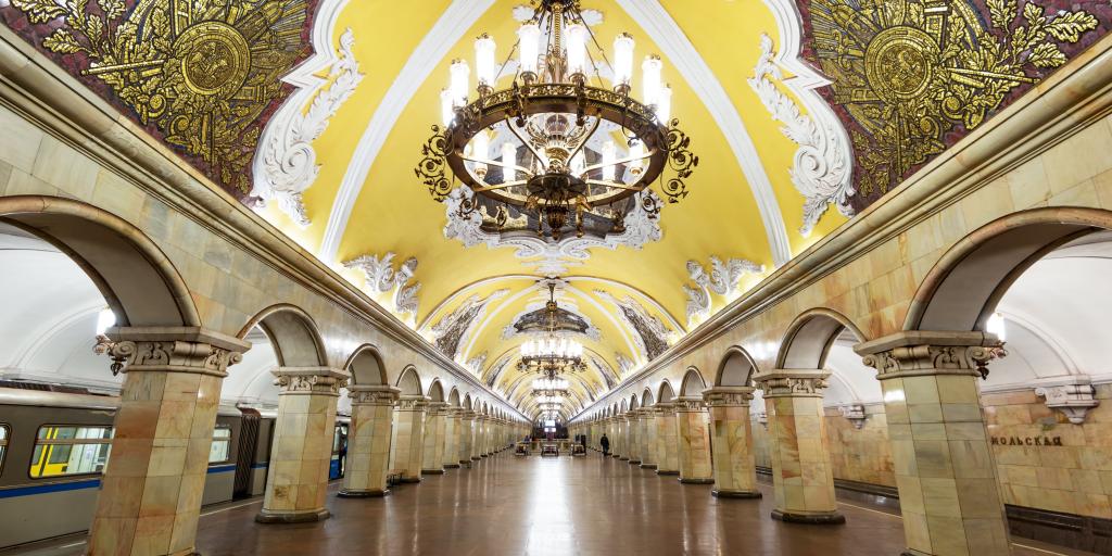 The ornate interior of Komsomolskaya metro station with a yellow Baroque style ceiling and stone arches