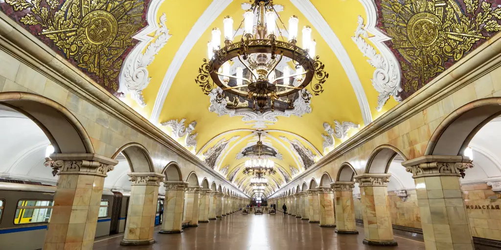 The ornate interior of Komsomolskaya metro station with a yellow Baroque style ceiling and stone arches