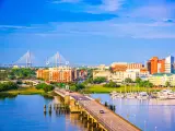 City's skyline over Ashley River with tall buildings and a suspension bridge seen in the distance