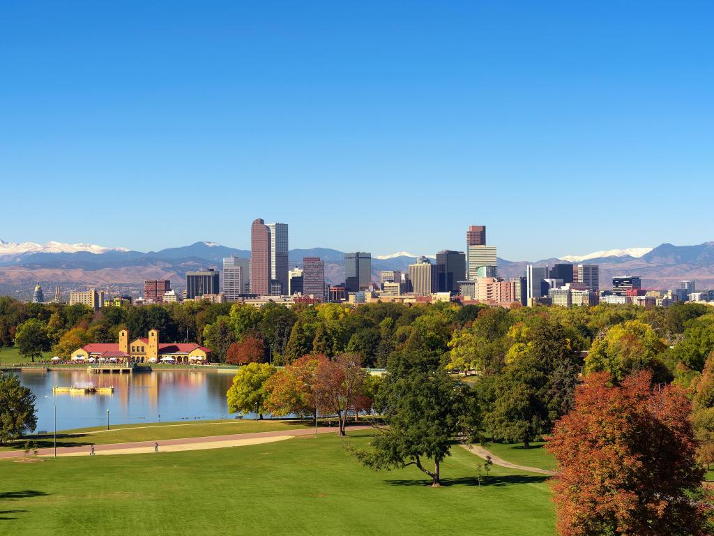 City skyline of Denver Colorado downtown with snowy Rocky Mountains and the City Park Lake. Large panorama.