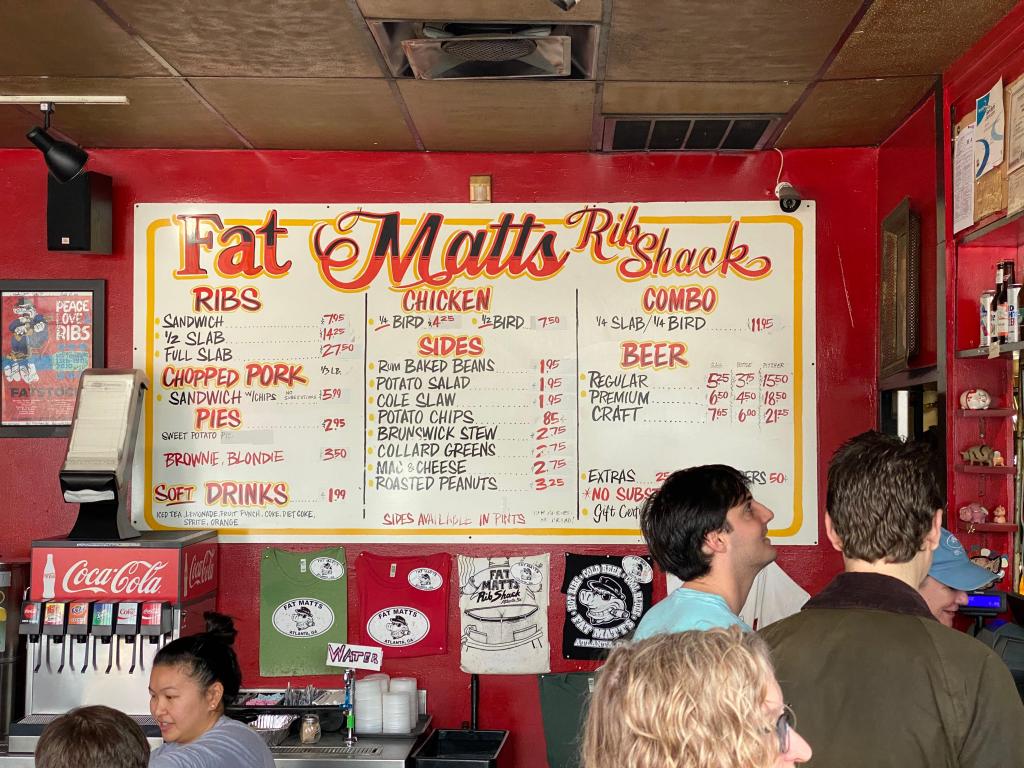 Close up view of the menu board inside Fat Matt's Rib Shack, a BBQ Restaurant in Atlanta, with patrons in the foreground