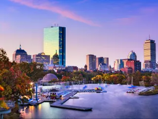 Boston, Massachusetts, USA skyline with water in the foreground at dusk.