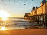 Early morning by the ocean. Wooden old pier leaving in the sea with wooden buildings. Birds flying in the sky. USA. Portland. Maine.