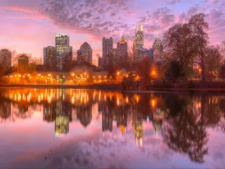 Panoramic view of Lake Clara Meer, with Piedmont Park Aquatic Center illuminated at dusk and Midtown Atlanta skyline in the background