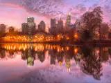 Panoramic view of Lake Clara Meer, with Piedmont Park Aquatic Center illuminated at dusk and Midtown Atlanta skyline in the background