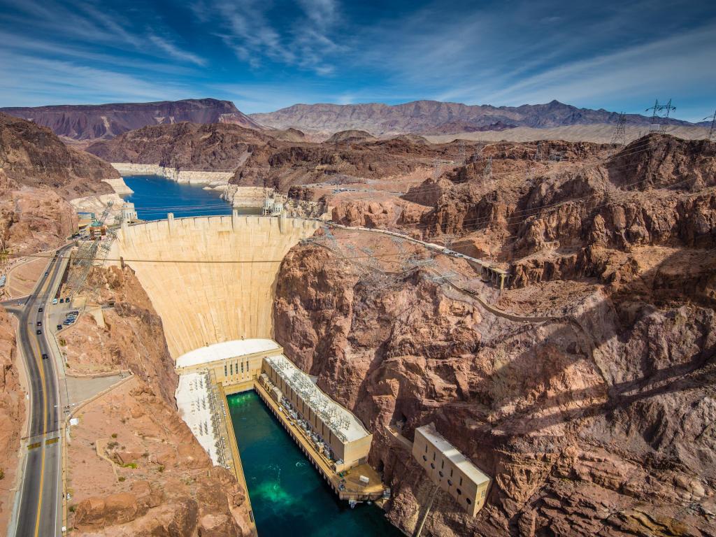 Aerial wide angle view of famous Hoover Dam, a major tourist attraction located on the border between the states of Nevada and Arizona, on a beautiful sunny day with blue sky and clouds in summer, USA