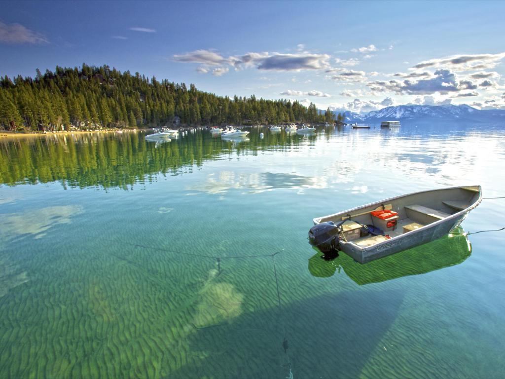 Calm clear water in lake Tahoe, with Trees and Mountains in the background