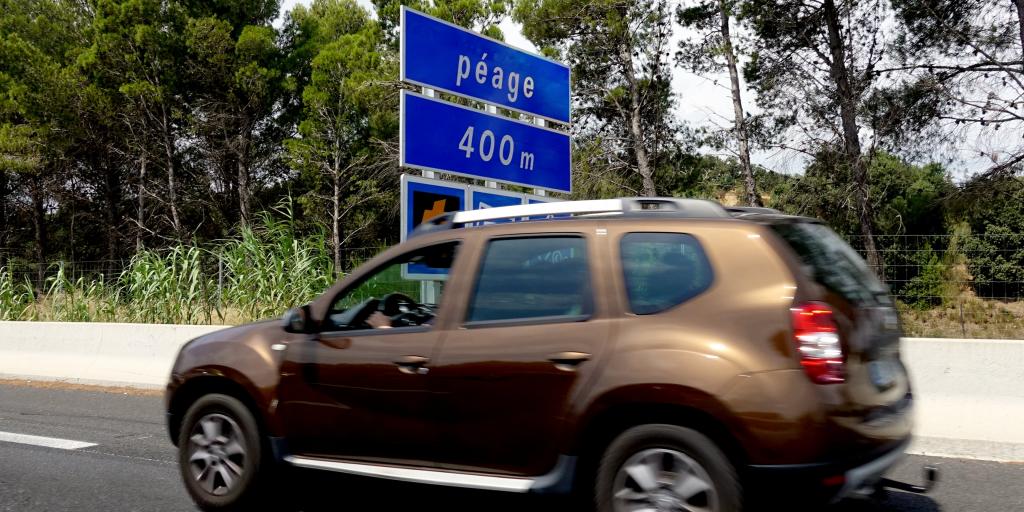 A bronze car on a French road with a blue 'Péage 400m' sign in the background