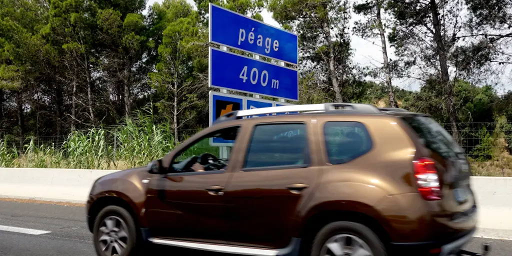 A bronze car on a French road with a blue 'Péage 400m' sign in the background