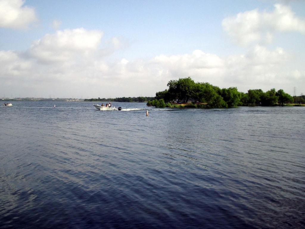 View across Calaveras Lake, with view of speedboat crossing the calm, blue waters, San Antonio, Texas