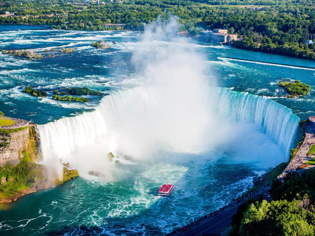 Niagara Falls aerial view with a red tour boat in the middle of a misty Horseshoe Falls