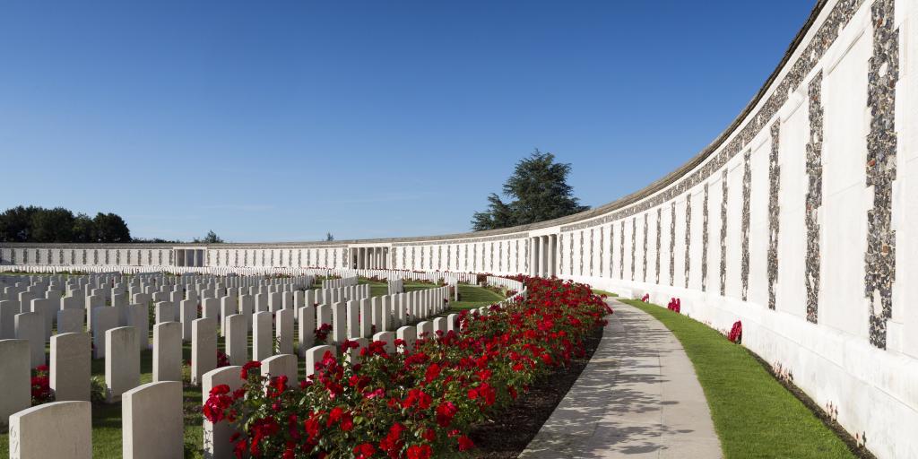 Poppies growing between white war graves at Tyne Cot World War One Cemetery on a sunny day