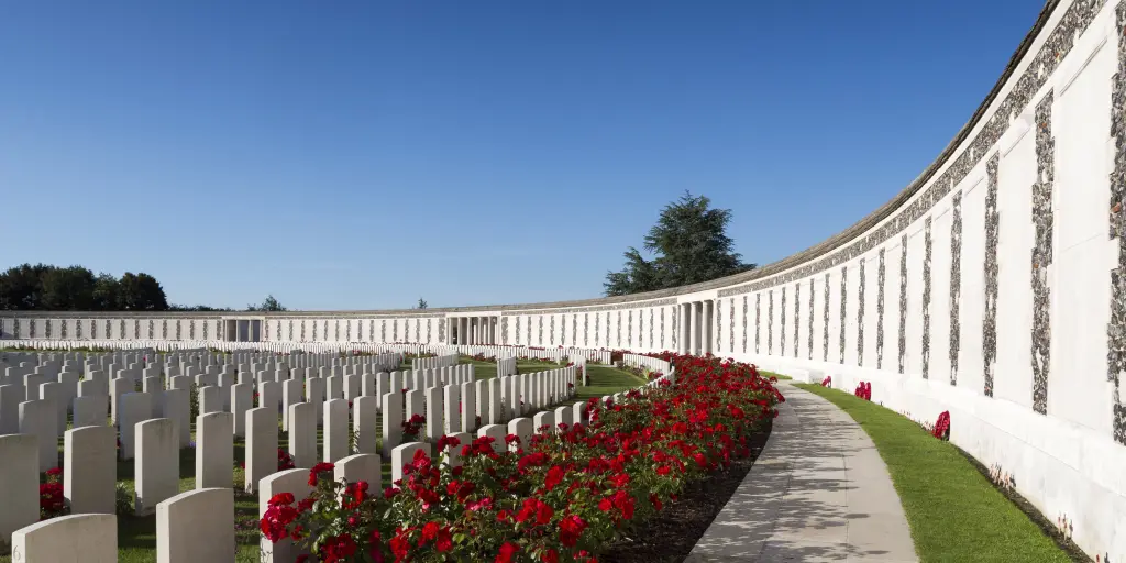 Poppies growing between white war graves at Tyne Cot World War One Cemetery on a sunny day