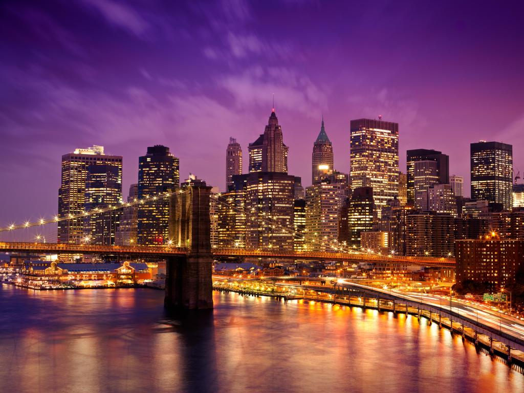 Skyline of downtown New York as the sun sets behind the fully lit buildings. 