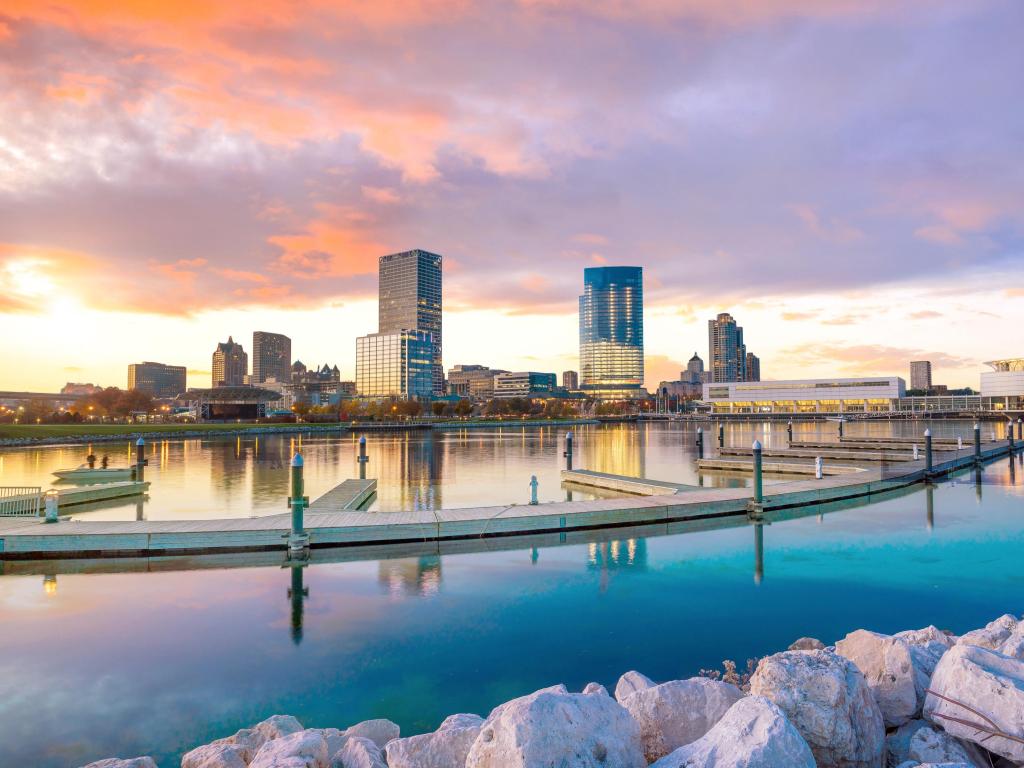 Milwaukee, Wisconsin, USA with the city skyline in the distance taken at twilight with the city's reflection in Lake Michigan and the harbor pier.