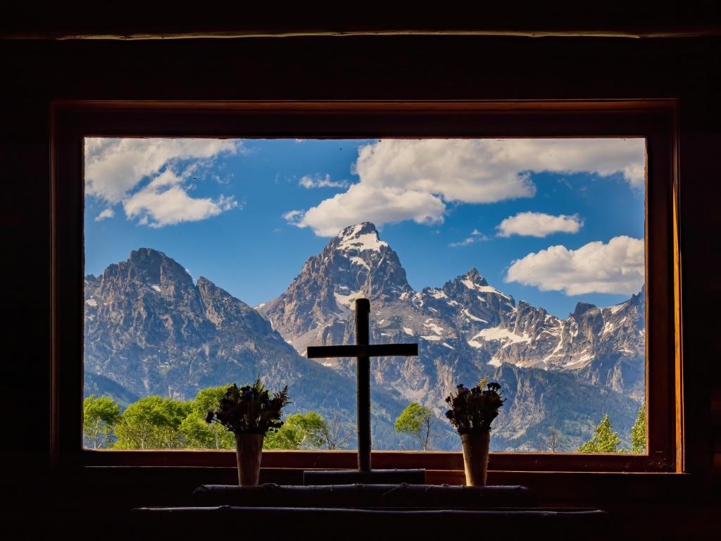 View of the Tetons from the window of Chapel of Transfiguration, with a cross in the middle