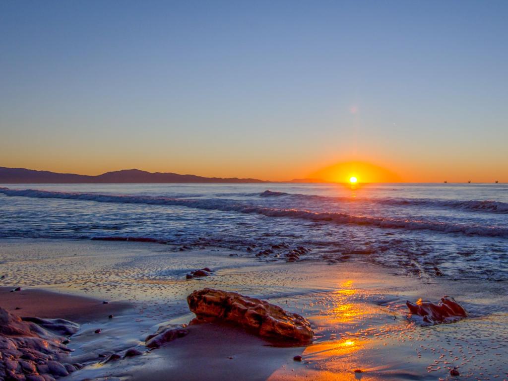 Santa Barbara, California, USA taken at sunrise with a beach view, rocks in the sand and the sea in the distance.