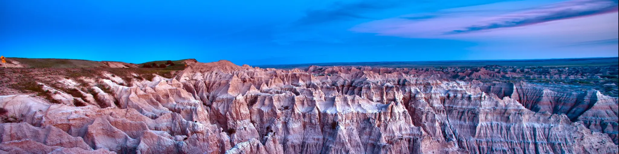 Badlands National Park at dusk with a full moon casting light over the jagged terrain