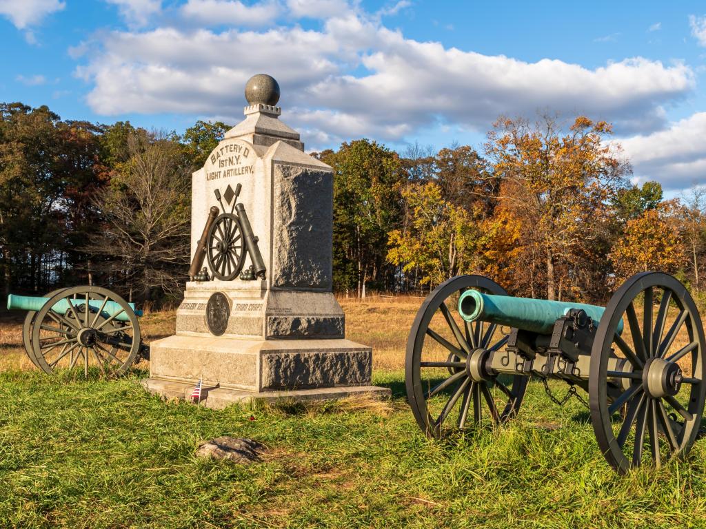 A Union monument and civil war cannons in the Wheatfield on the Gettysburg National Military Park on a sunny fall day.