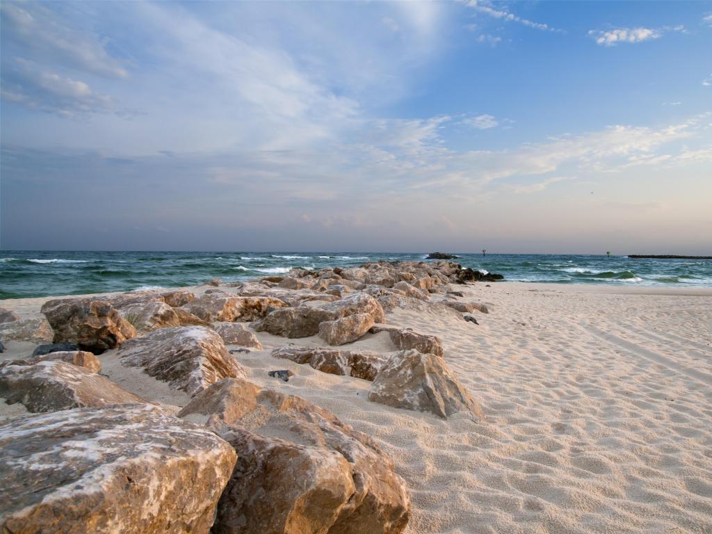 Gulf Coast, Alabama, USA with a beautiful beach with white sand and stones in the foreground, the sea in the distance taken on a sunny day.