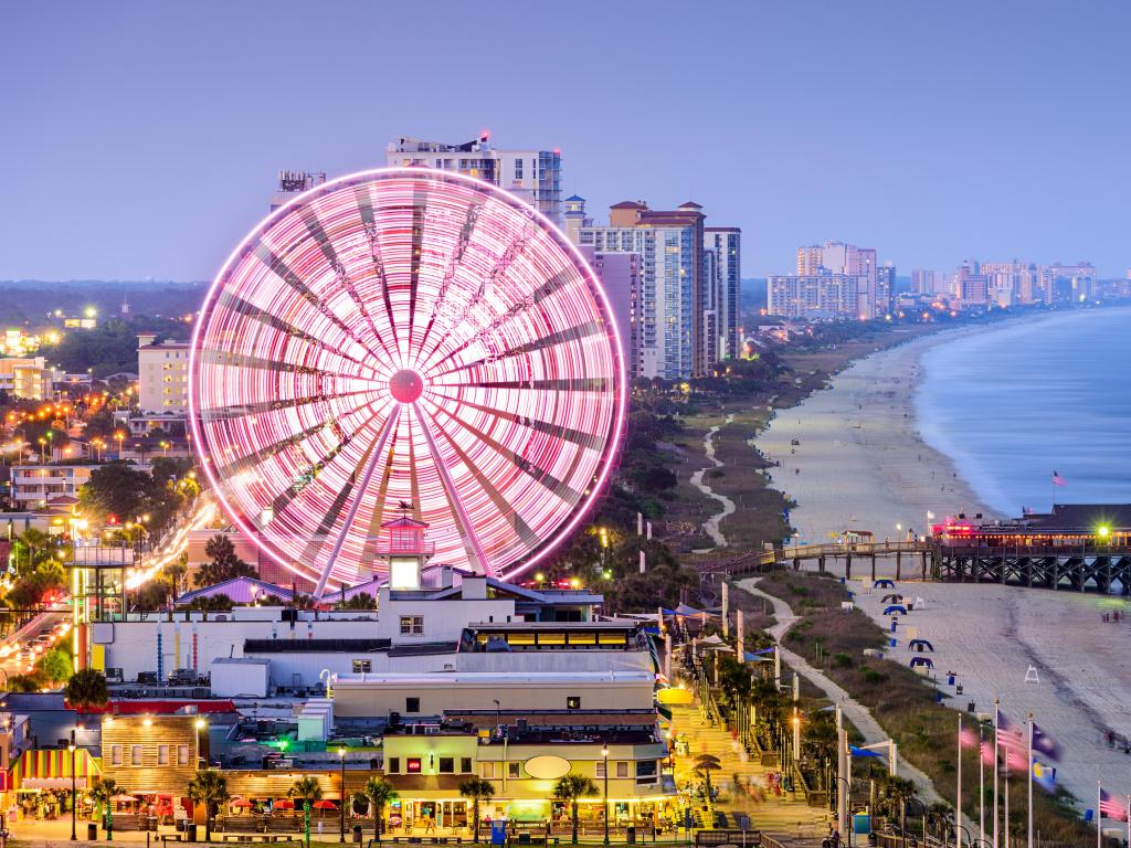 Myrtle Beach, South Carolina, USA city skyline with the rides and ferris wheel at early evening, the city skyline in the background against the beach and sea.
