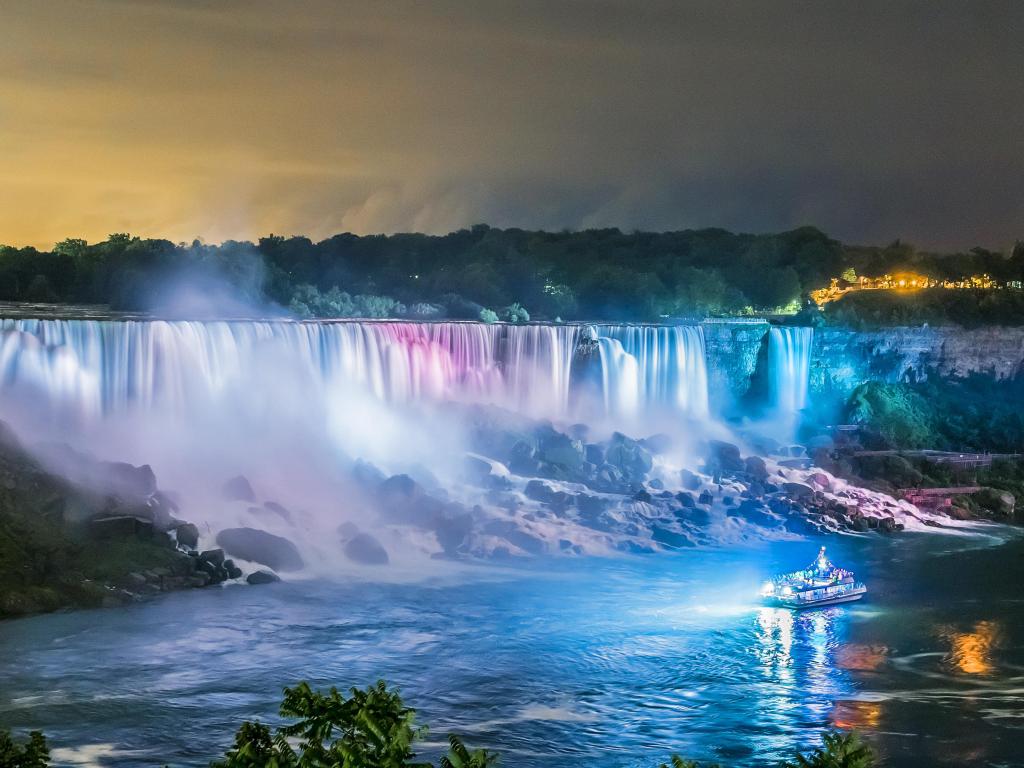 A boat tour at Niagara Falls, lit up at night with bright colors