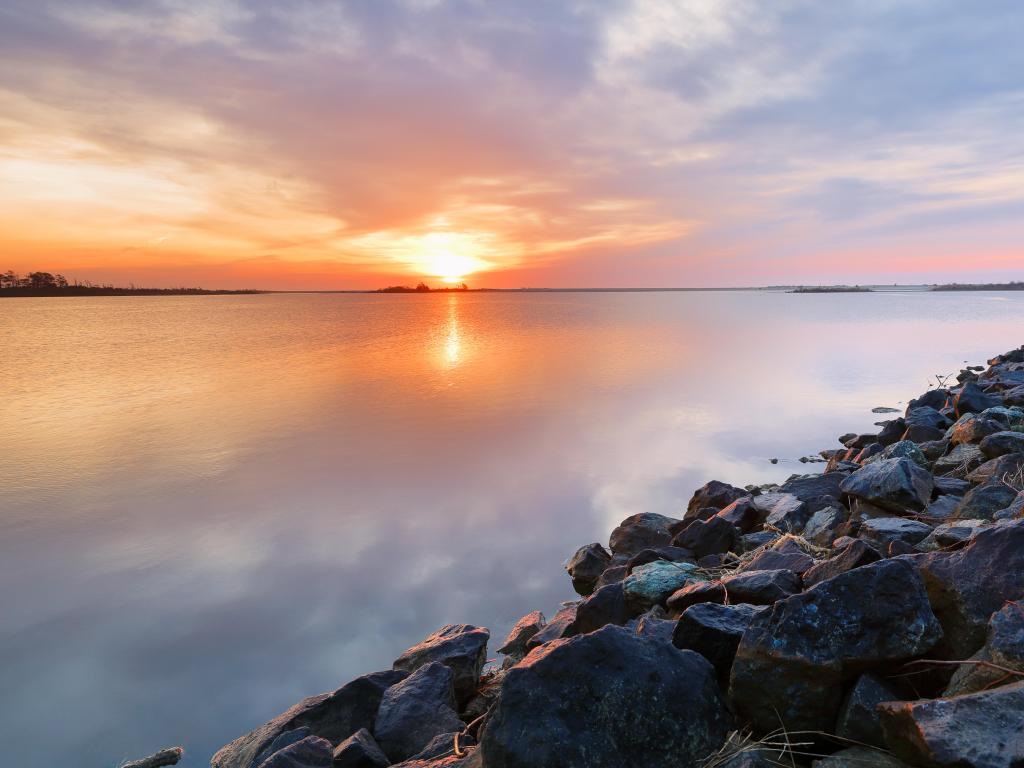 Chincoteague National Wildlife Refuge, Virginia, USA taken at sunrise with rocks in the foreground and a calm stunning lake in the distance.