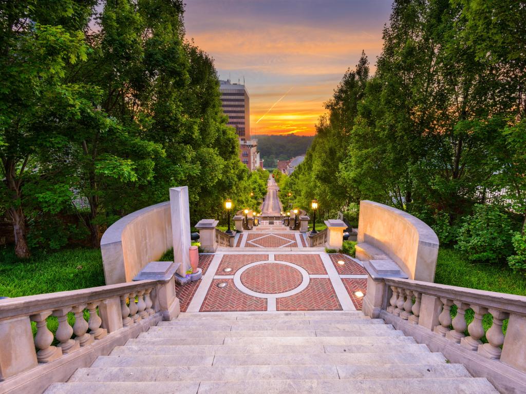 Lynchburg, Virginia, USA downtown at Monument Terrace looking down the steps with a sunset and trees in the distance.