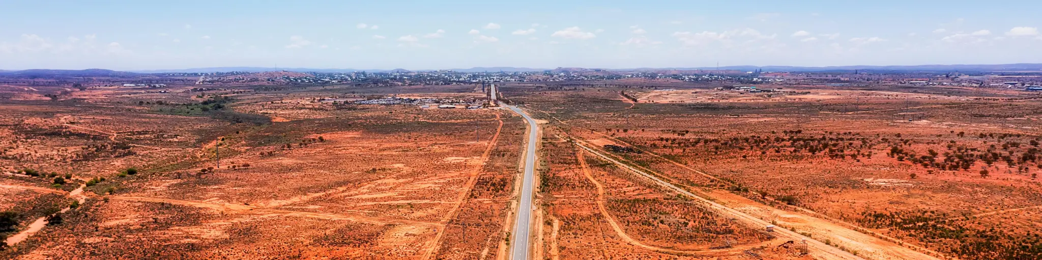 Australian red soil outback at the entrance of Broken Hill, highway running through the image