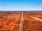 Australian red soil outback at the entrance of Broken Hill, highway running through the image