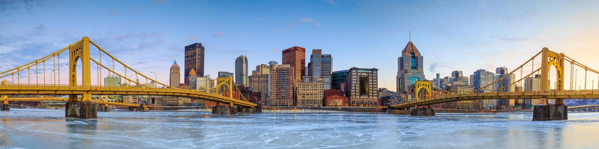 Panorama of downtown Pittsburgh at twilight, with skyscrapers and bridges across the waterfront