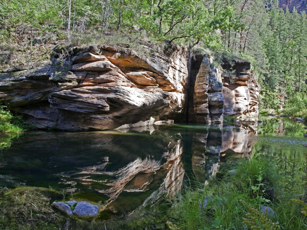 West Clear Creek Wilderness, Arizona, USA with rock formations and reflections in the water in the foreground and trees surrounding.