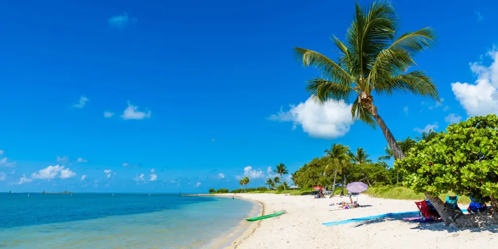 The white sand Sombrero Beach with palm trees and people sunbathing on Marathon island, Florida, USA. 