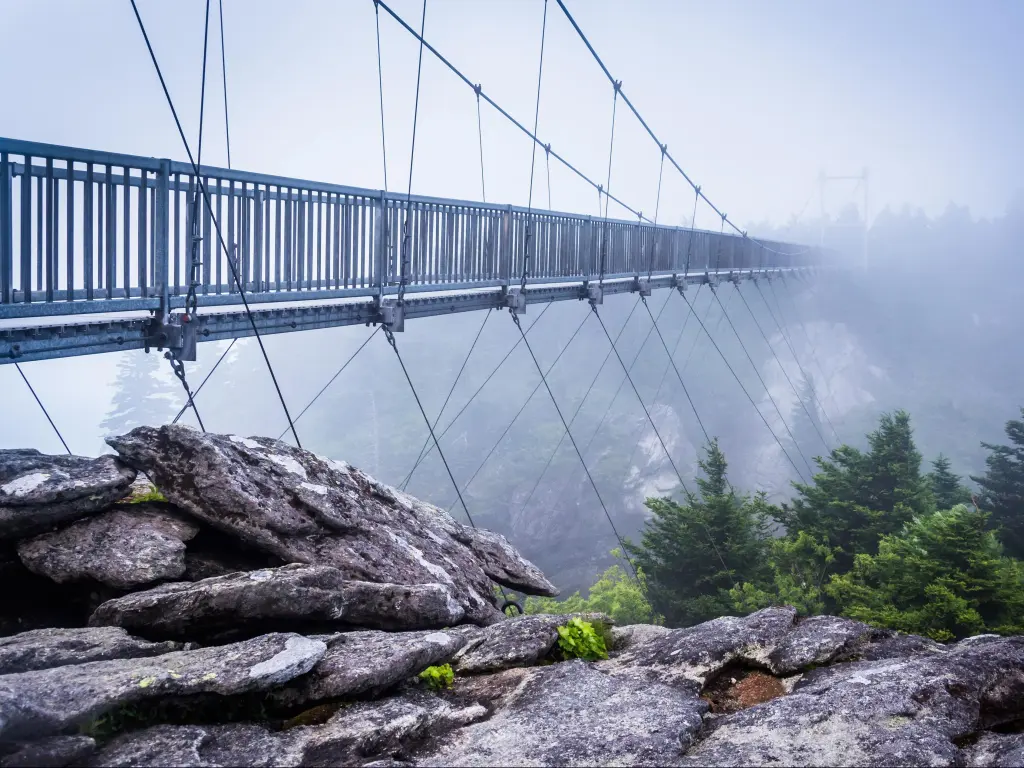 Footbridge crossing mountain valley leading into heavy fog