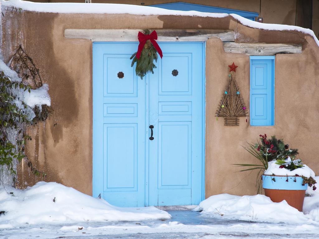 An entryway with a blue door in Santa Fe with Christmas decorations in New Mexico in winter.