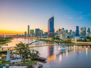 Brisbane, Australia at twilight with the city skyline in the background and the Brisbane river in the foreground.